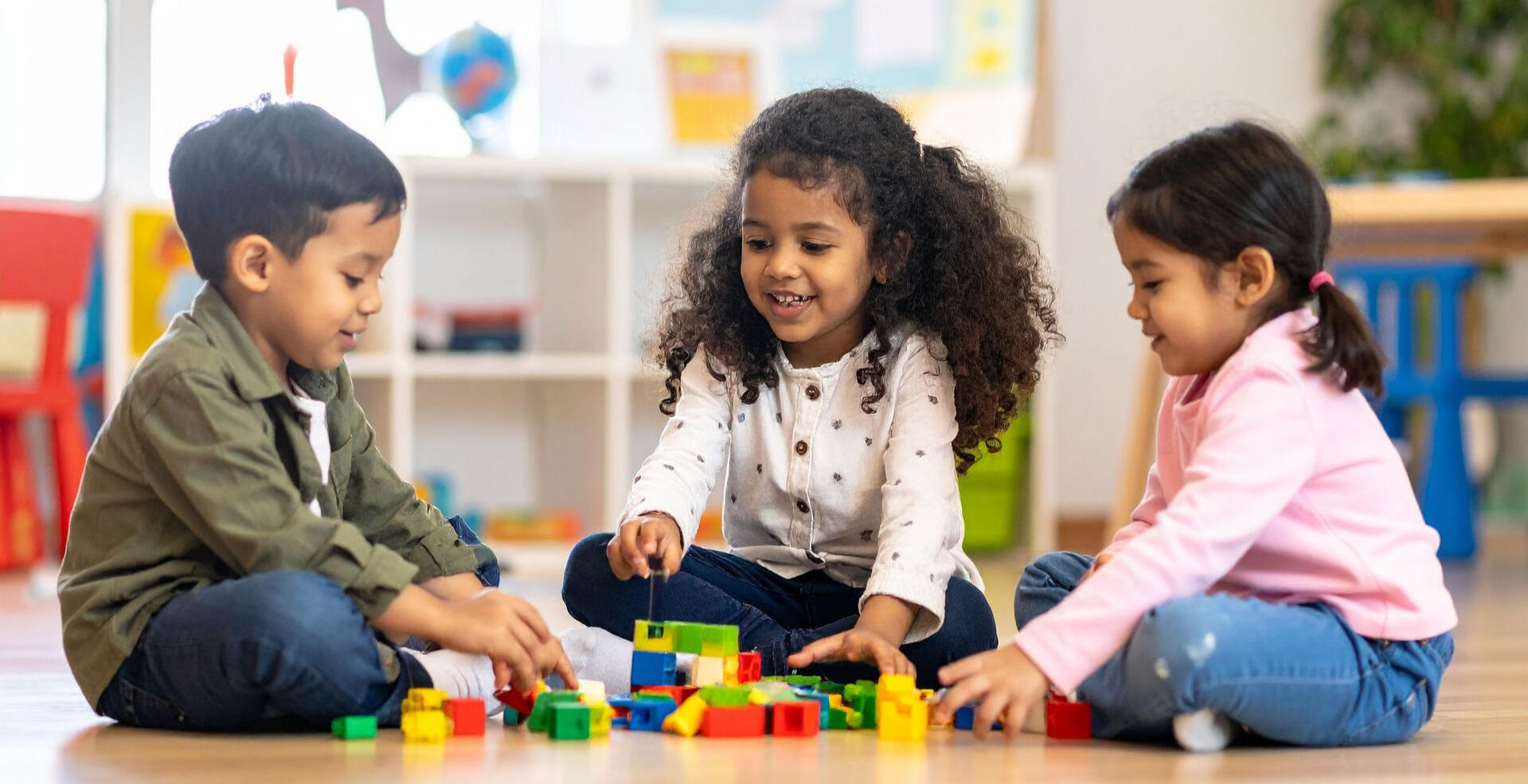 Investing in Education and Childcare Three Louisiana children playing with colorful building blocks on the floor